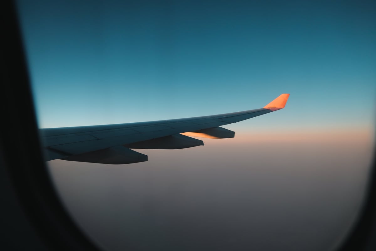 Airplane wing cutting through sunset skies