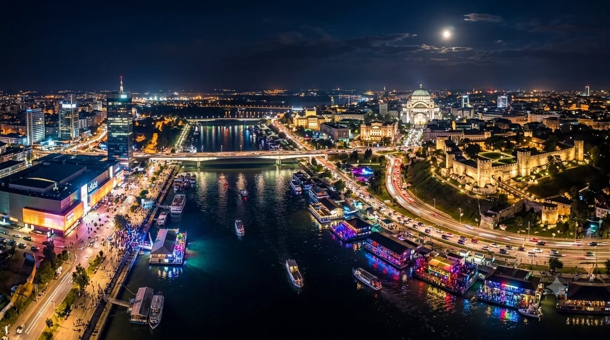 Aerial night view of Belgrade with the Sava and Danube rivers, illuminated Belgrade Fortress, Temple of Saint Sava, and riverside floating clubs